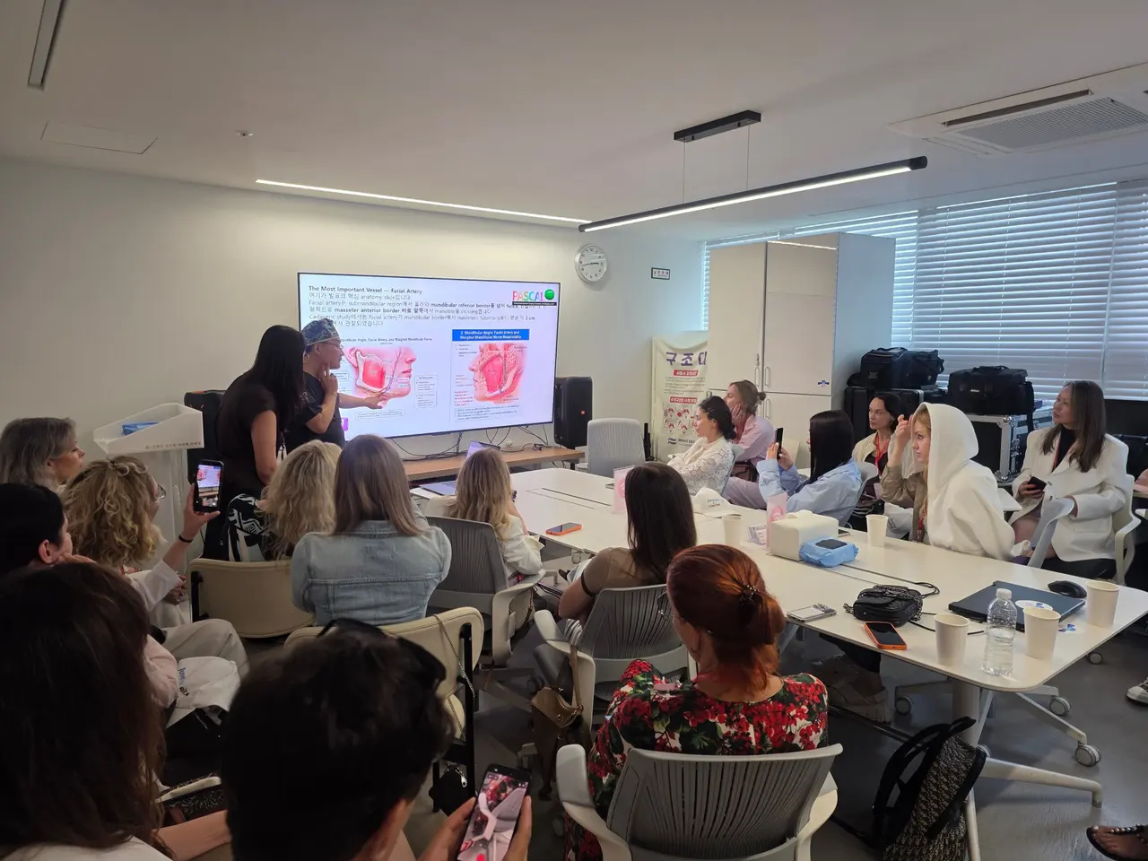Visiting dermatologists watching a lecture with an anatomy slide during the H.A.R.T program at Pascal Clinic