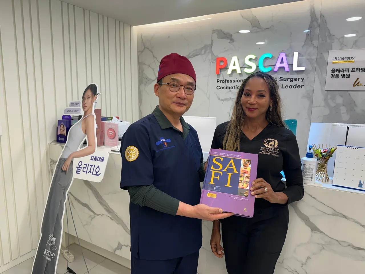 A Pascal doctor holding the SAFI fat grafting book with a visitor at the Pascal Clinic reception